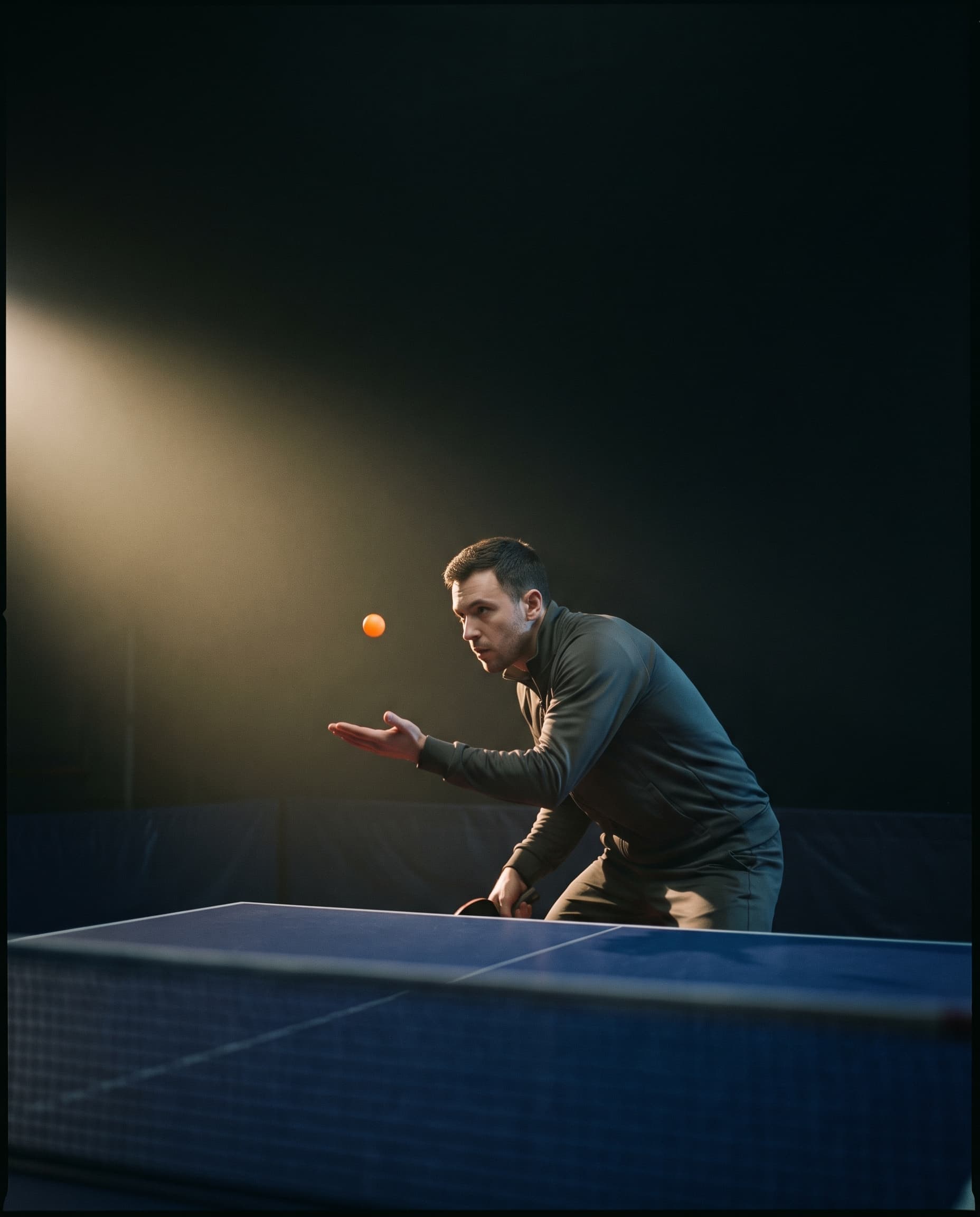 A player frozen at the moment of a serve toss in a dark tournament hall